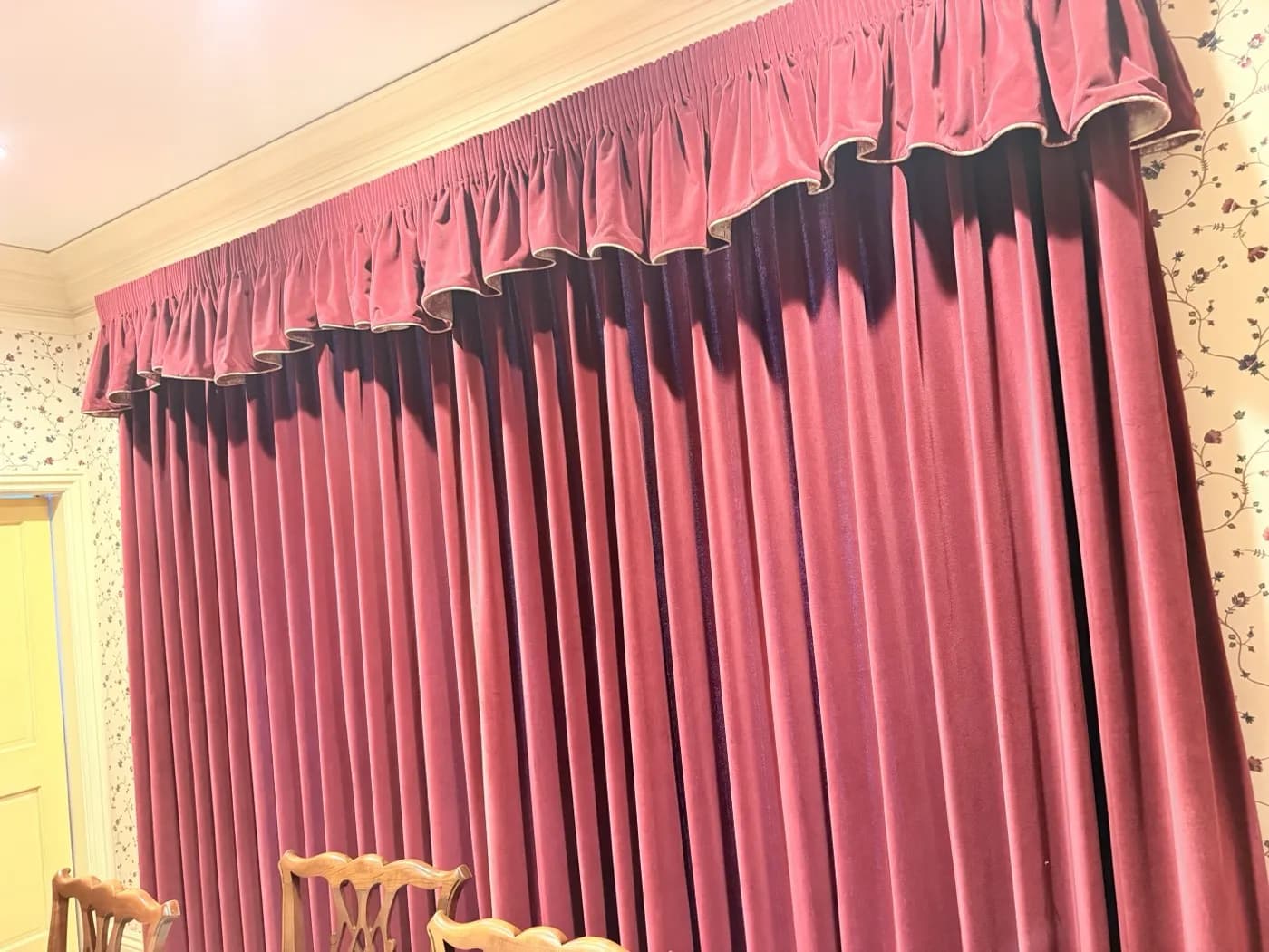 Long red velvet drapes with a gathered valance in a dining room