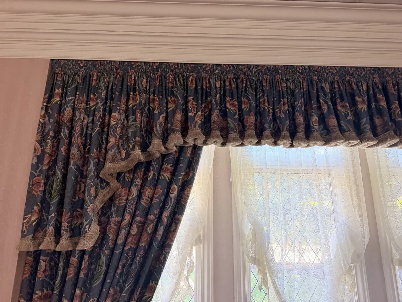 Floral lined drapes with a gathered valance and lace sheers on a bay window