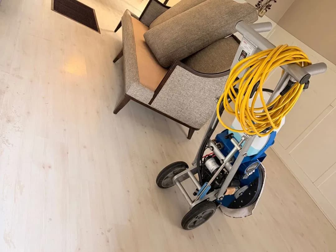 Floor cleaning machine on a light wood floor next to a chair